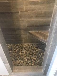 Plank tile shower with pebble stone floor.