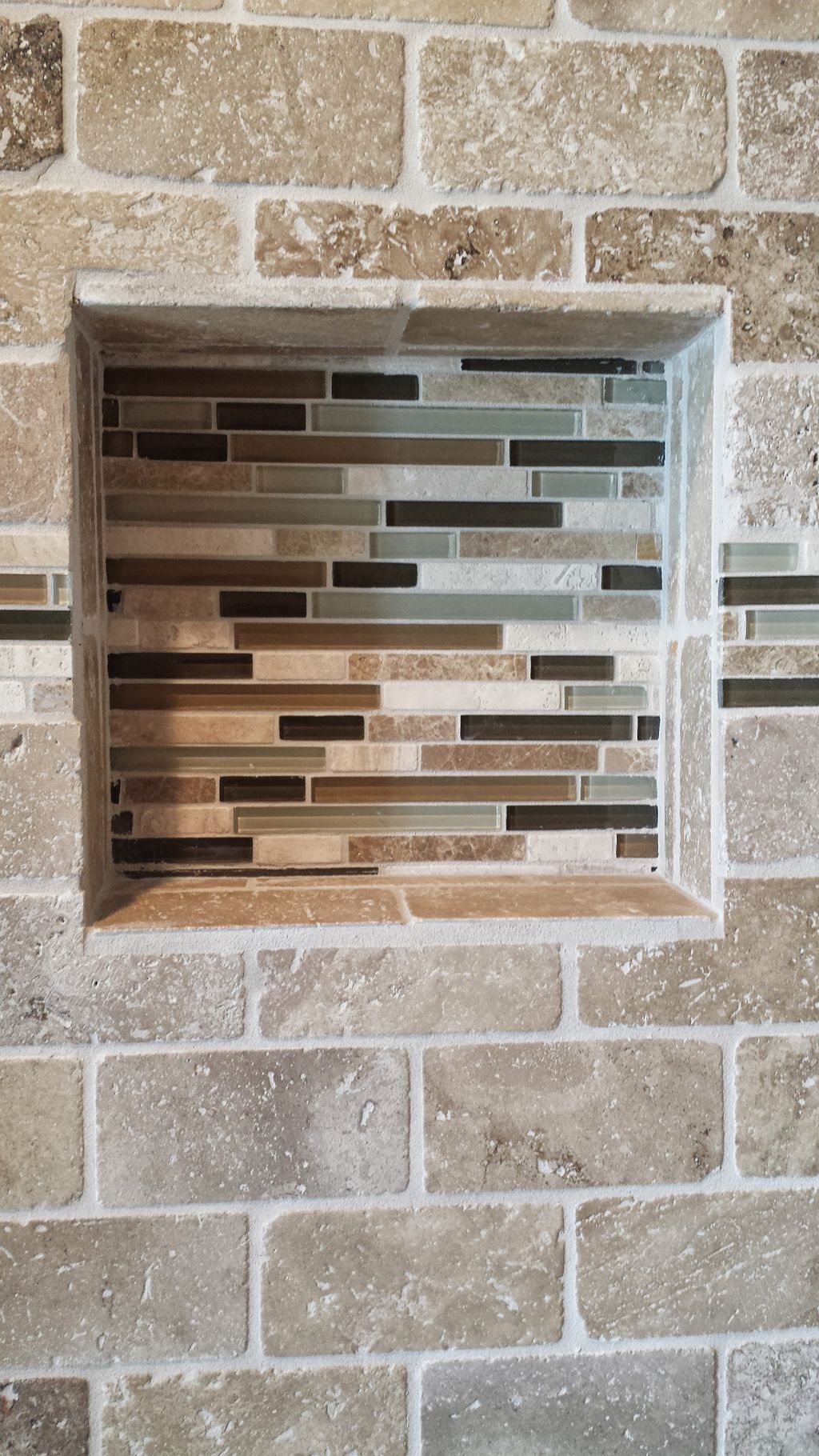 Shower shelf built into the wall.  Glass tile acce