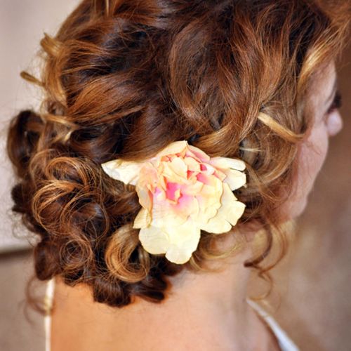 Romantic curly up-do with an accent flower.