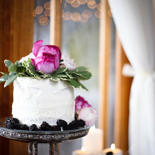 A whimsical white cake topped with fresh peonies.