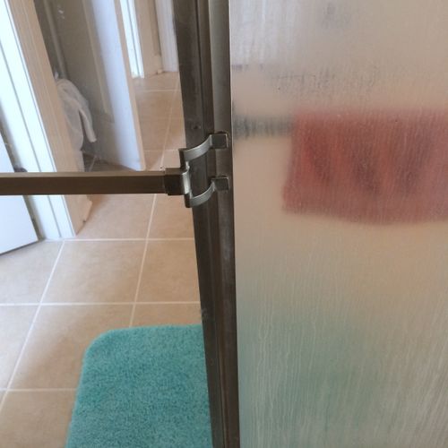 On the top, soap scum on a shower door, on the bot