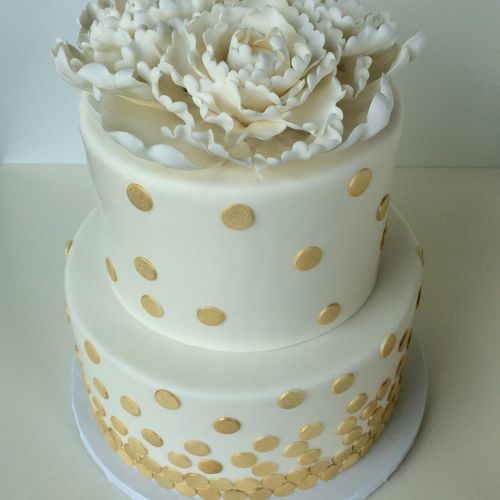 A stunning white wedding cake with gold dot accent