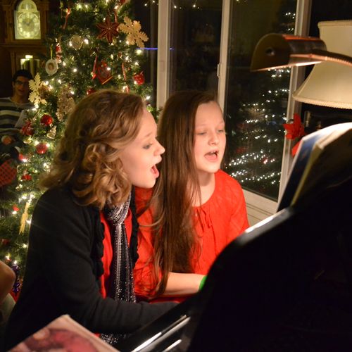 Two students playing a duet on the piano and singi