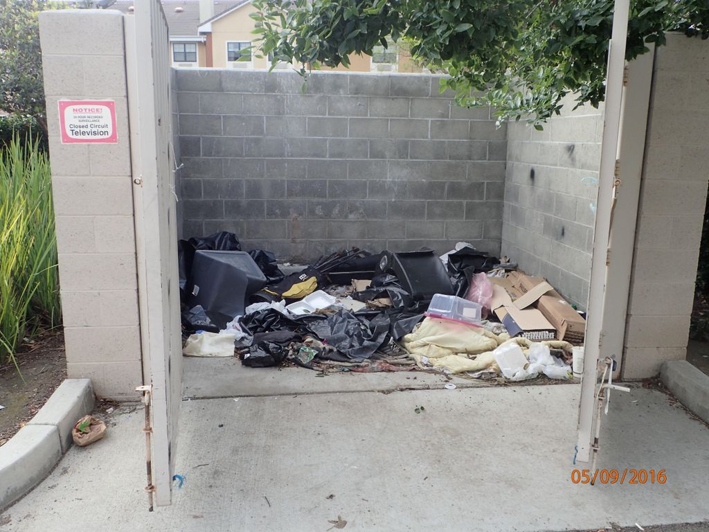 Trash people left behind in a dumpster enclosure.
