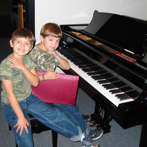 Siblings having fun at piano lesson.