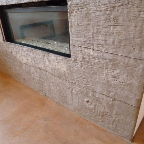 Concrete fireplace with wood grain texture.