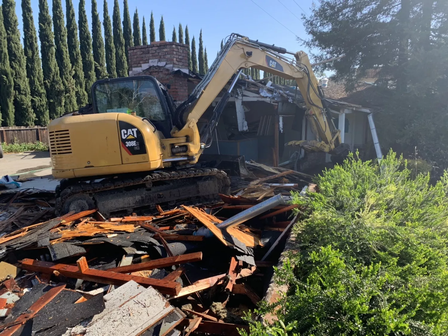 Yellow CAT excavator demolishing a house