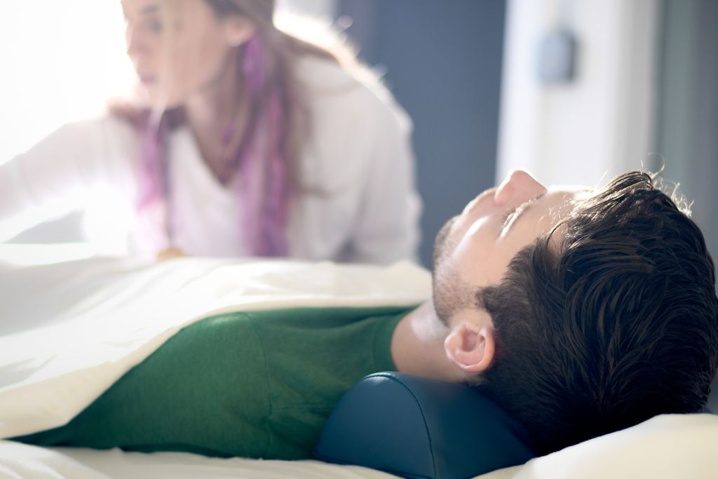 Participants in a Reiki session lie on a massage t