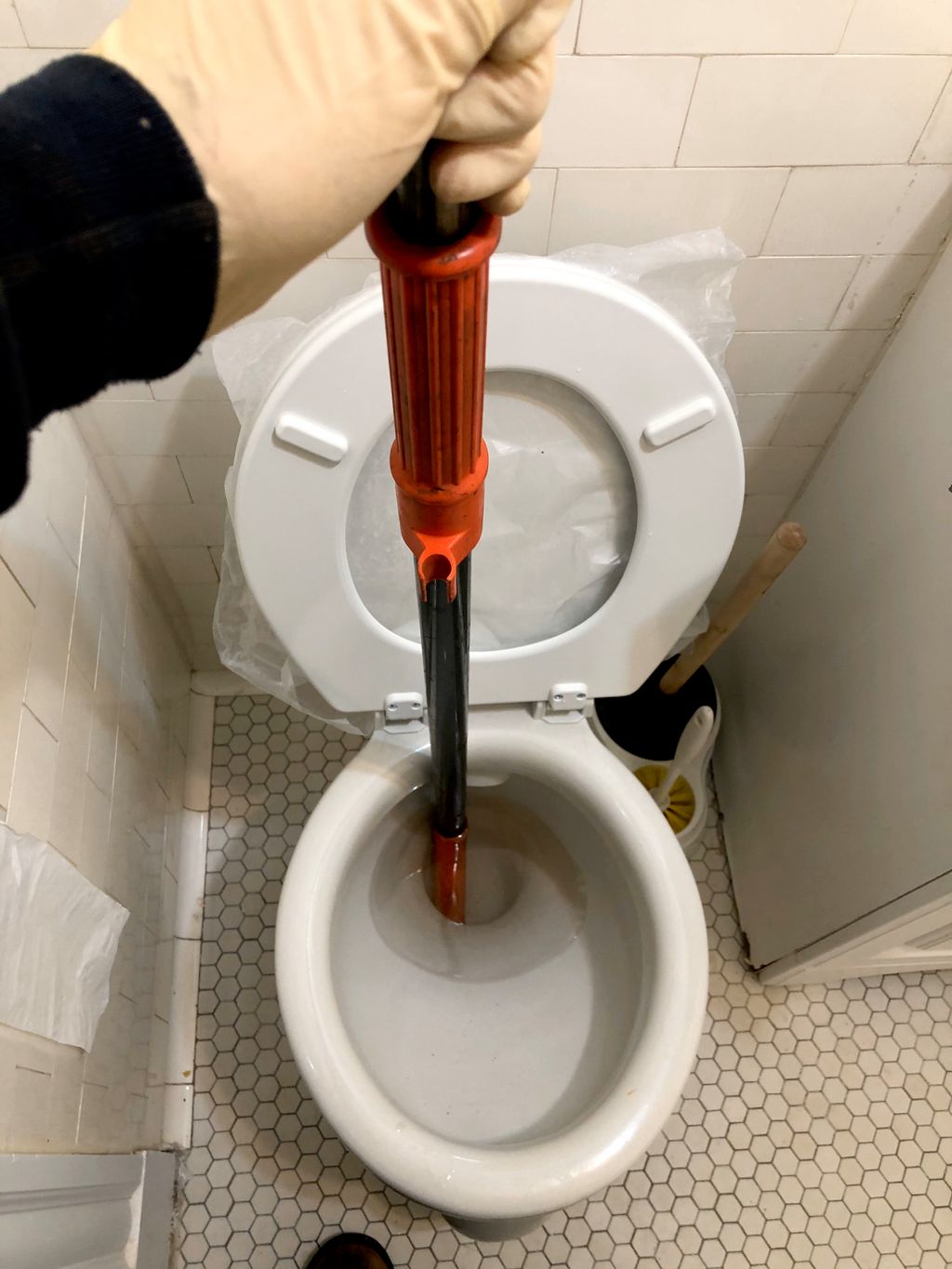 Auguring a toilet to dislodge blockage.