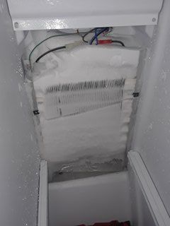 freezer section of refrigerator covered with ice