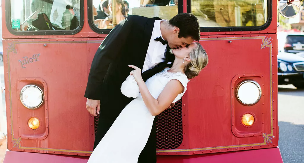 groom and bride kissing in front of bus