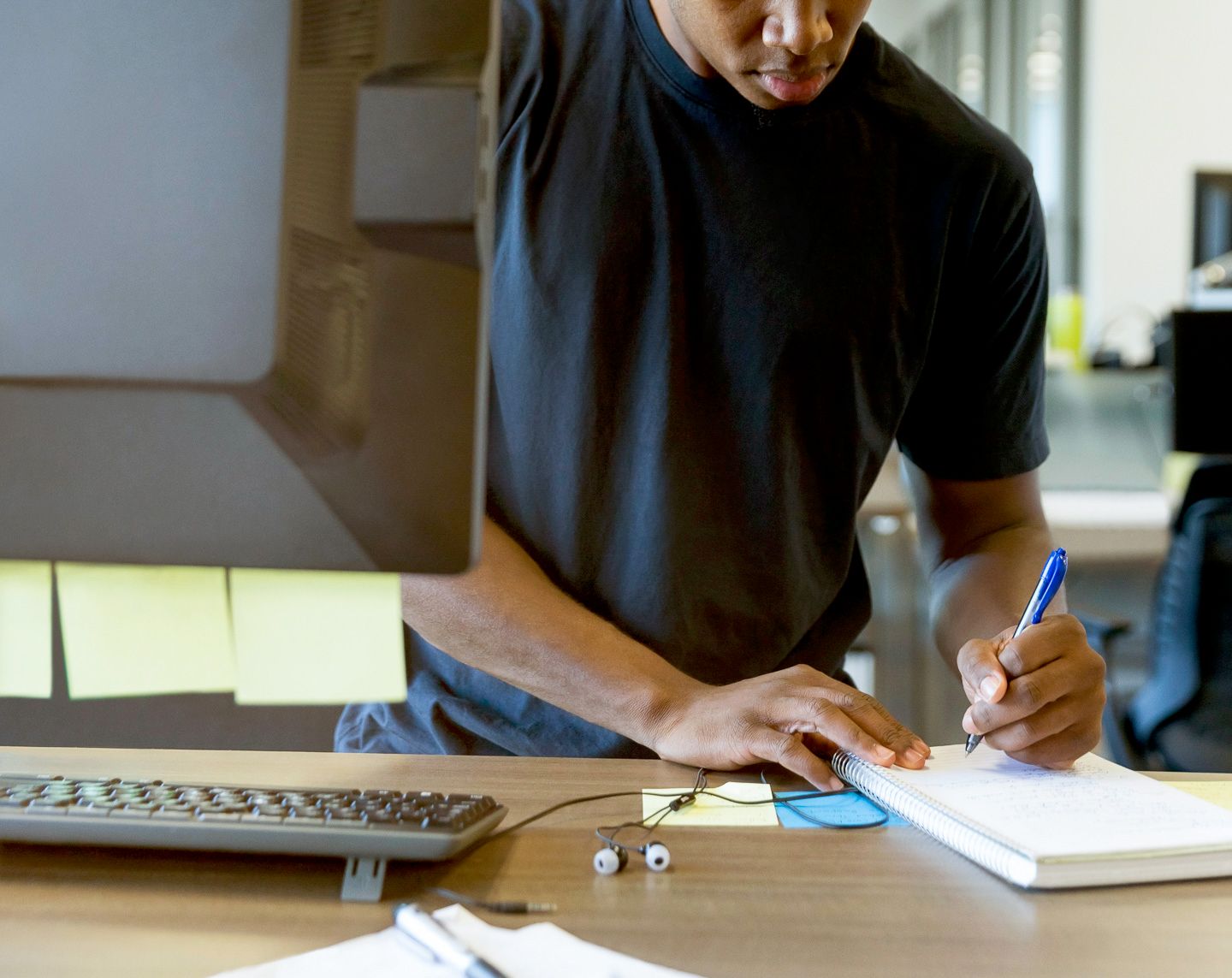 male writing on piece of paper at table