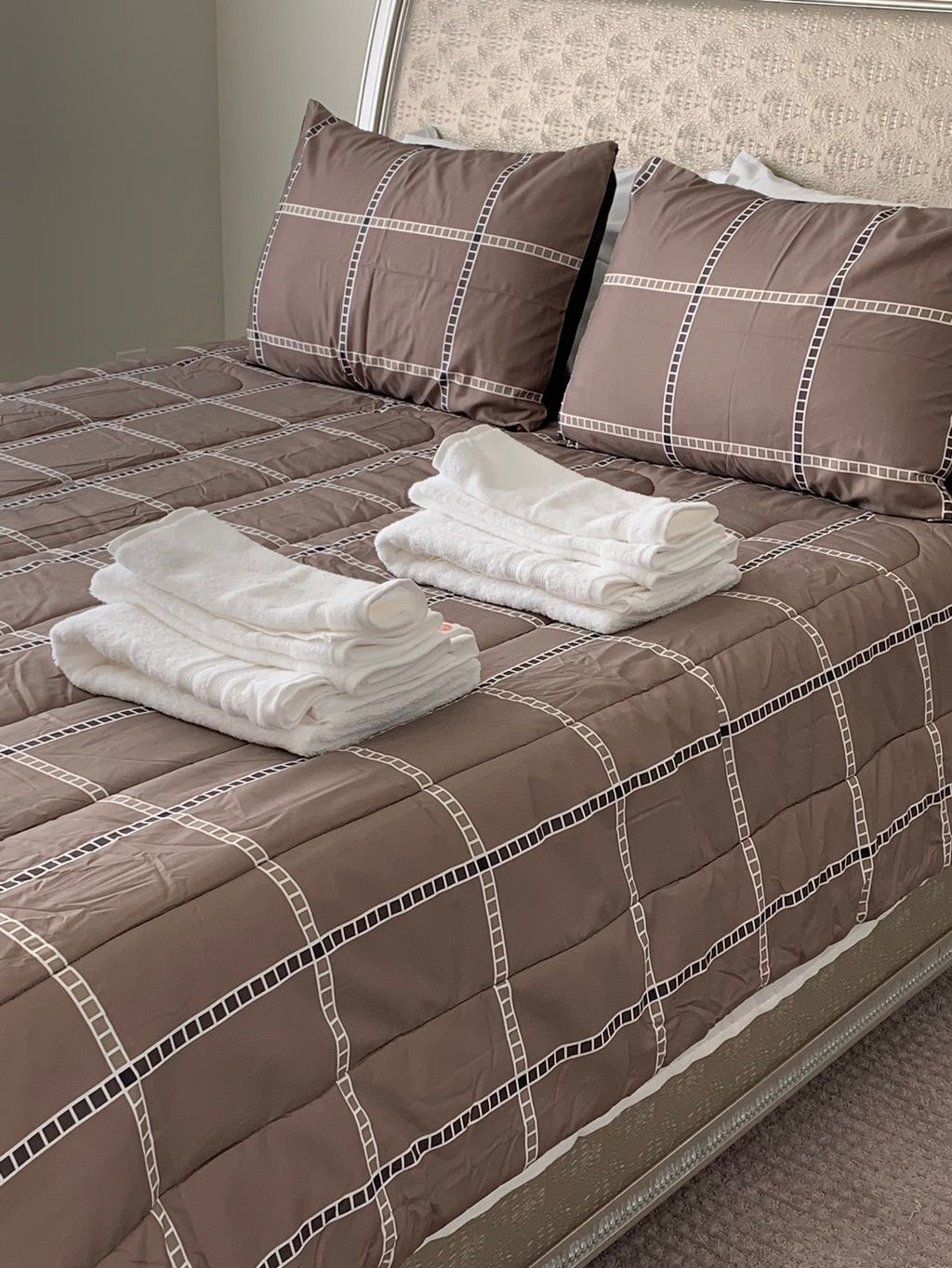 Freshly made bed with his and hers towels laid out
