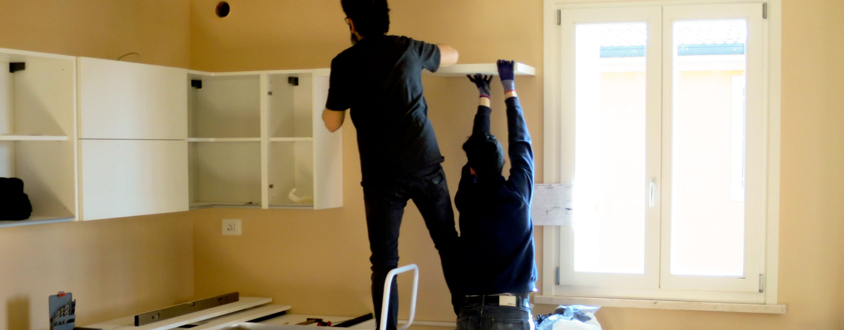 men adding shelves and cabinets to kitchen