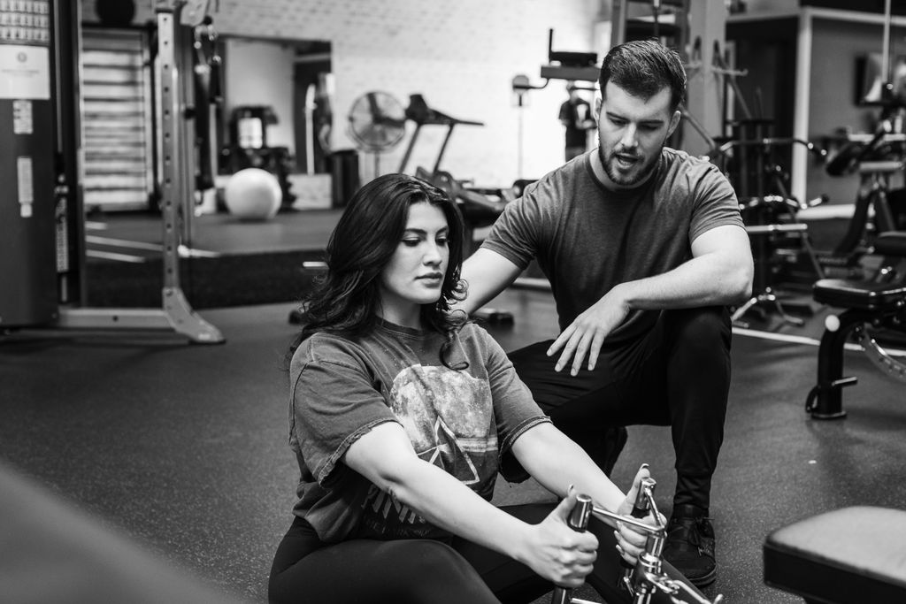 Nina performing a seated cable row, while I provid