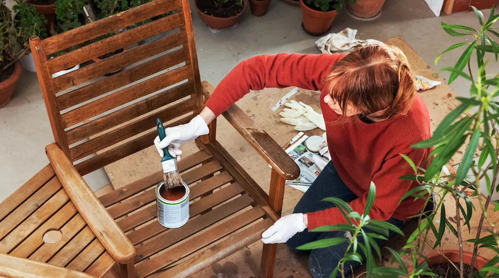 woman painting outdoor furniture