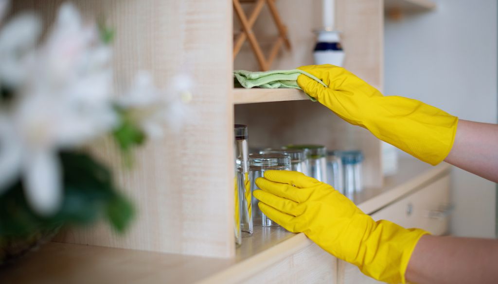 house cleaner dusting and wiping shelves