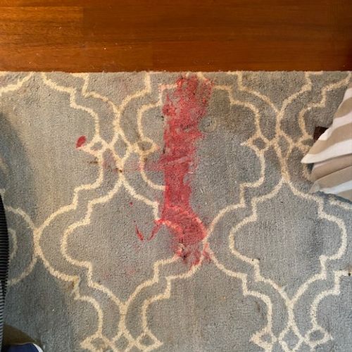 Red candle wax on wool rug before.