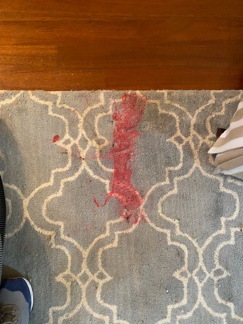 Red candle wax on wool rug before.