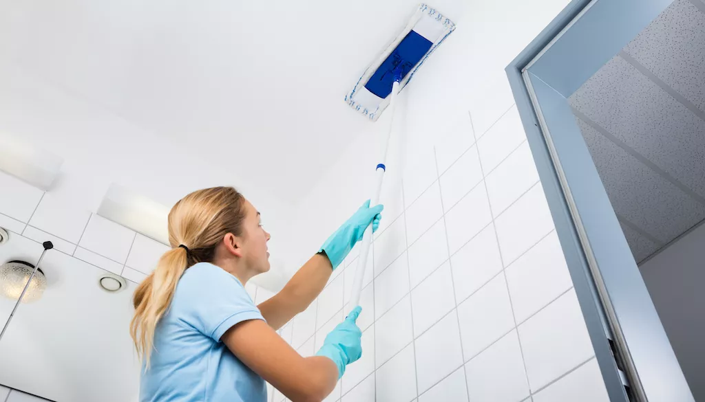 woman cleaning ceiling with mop