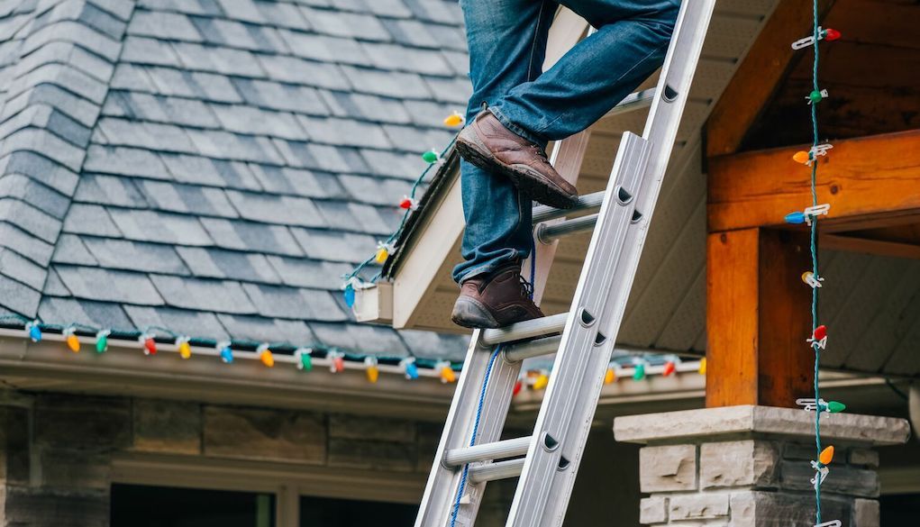 professional hanging up holiday lights on house