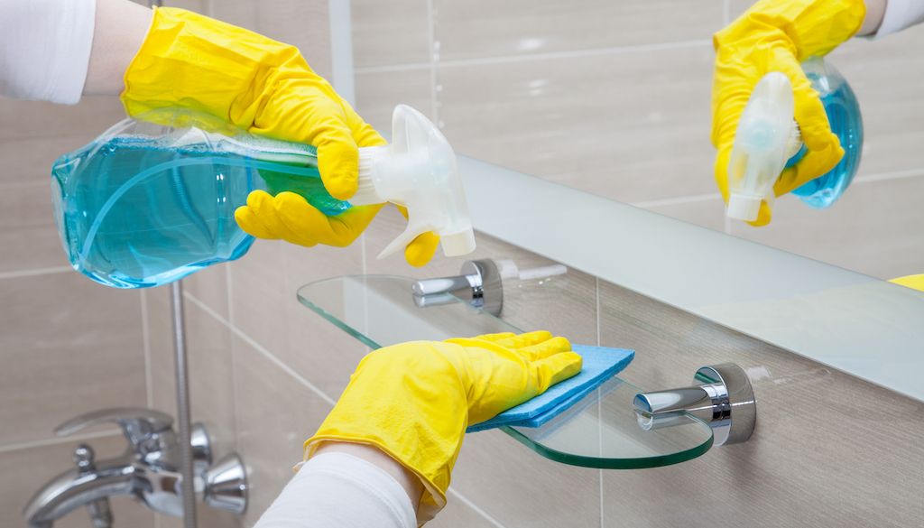 cleaning bathroom shelf with glass cleaner