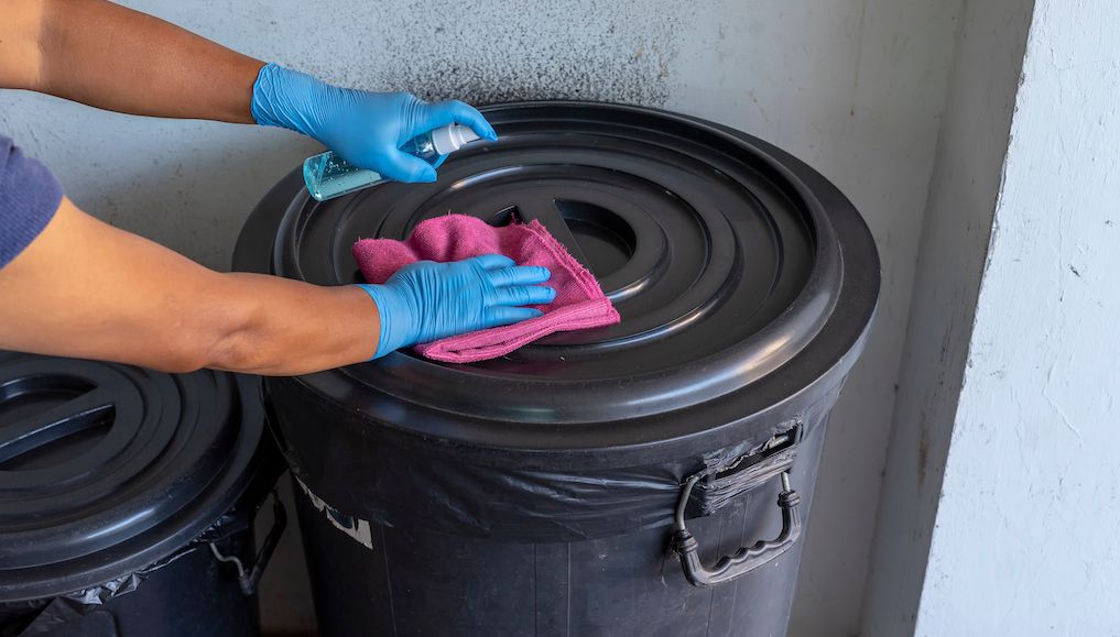 disinfecting and cleaning trash can with solution and rag