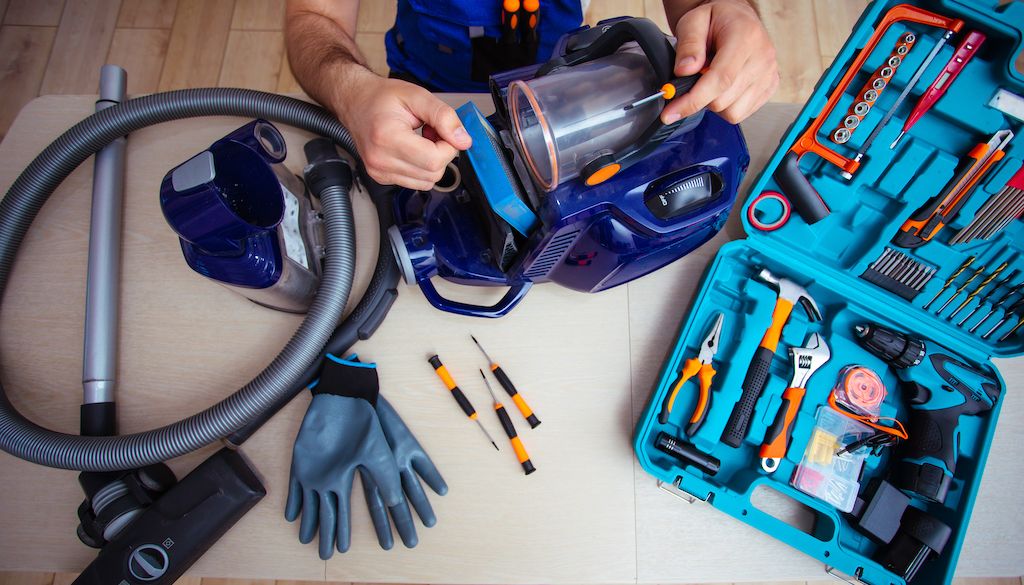 man sitting on floor and repairing vacuum cleaner