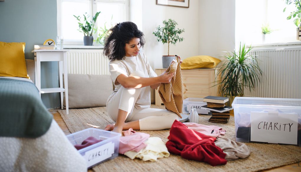 woman sitting on floor and organizing clothes in charity boxes