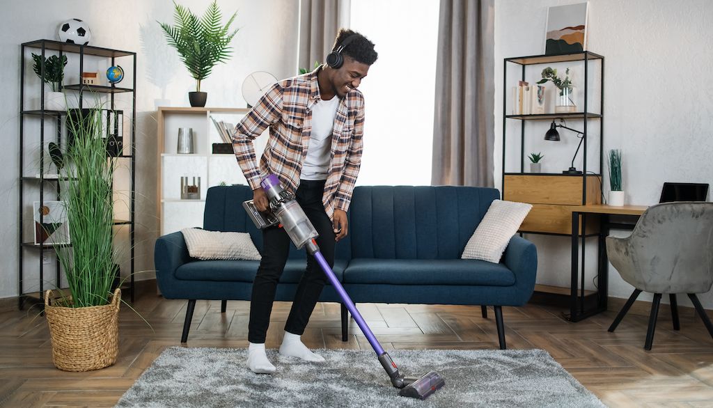 man with headphones on vacuuming living room rug