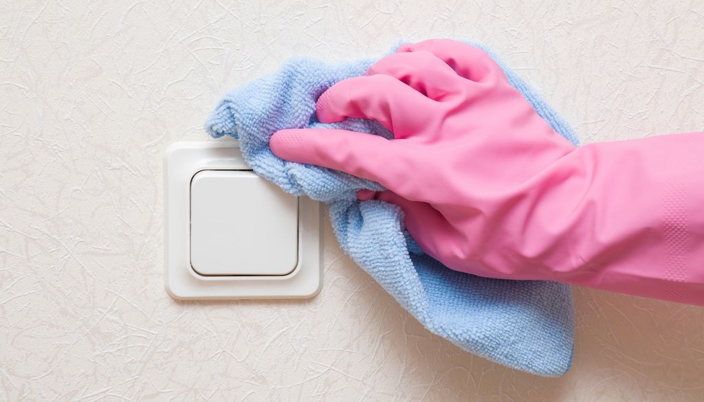 pink hand glove wiping wall around lightswitch