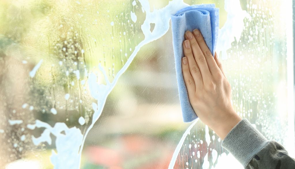 hand washing window with blue rag when it's sunny outside