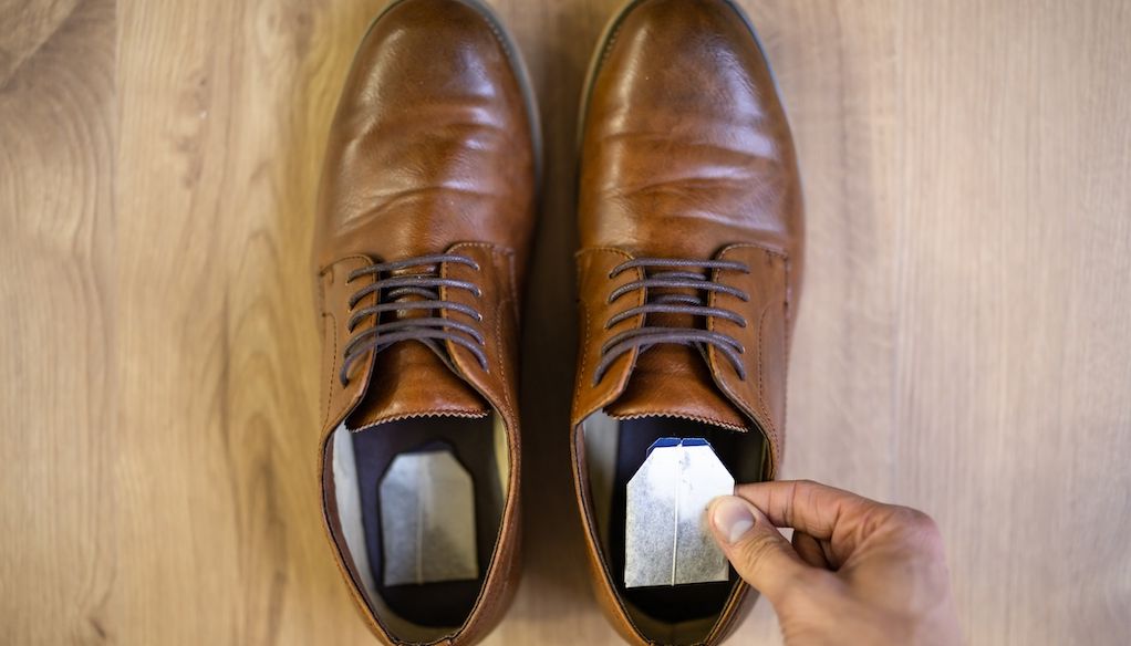 hand placing tea bags in dress shoes
