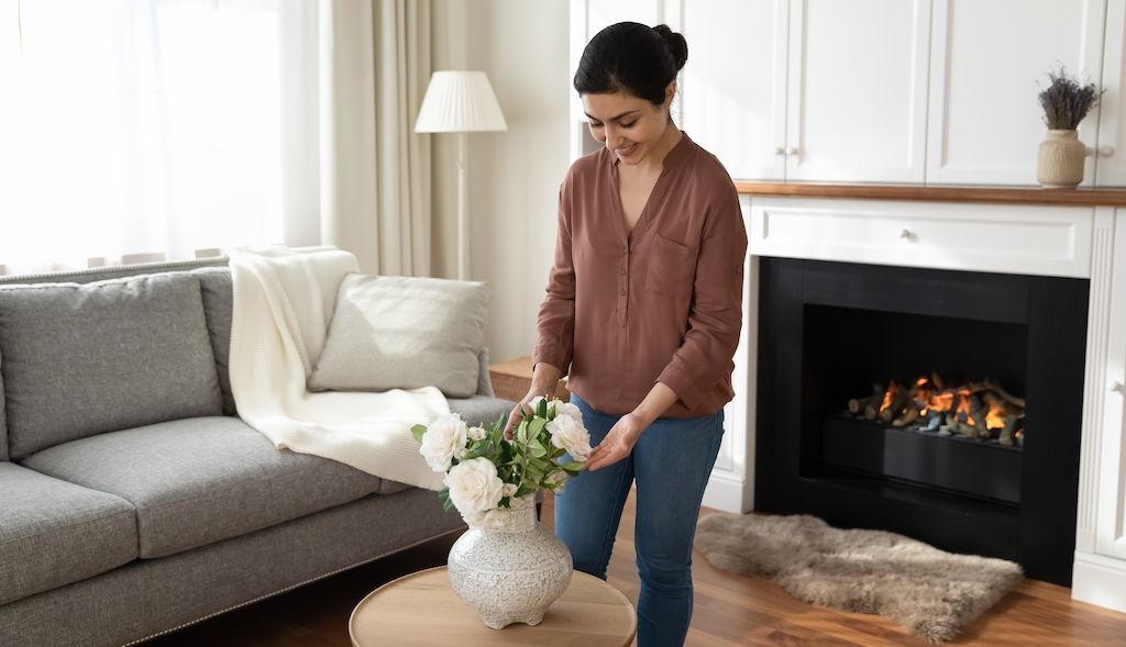 woman fixing flowers on living room coffee table