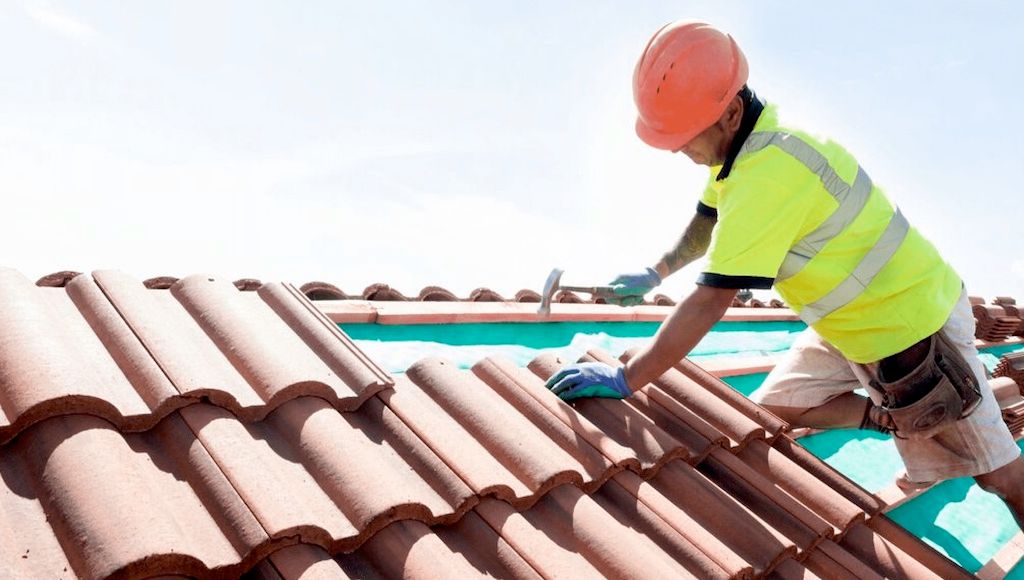 roofer on top of tile roof with hammer and shingle tiels 