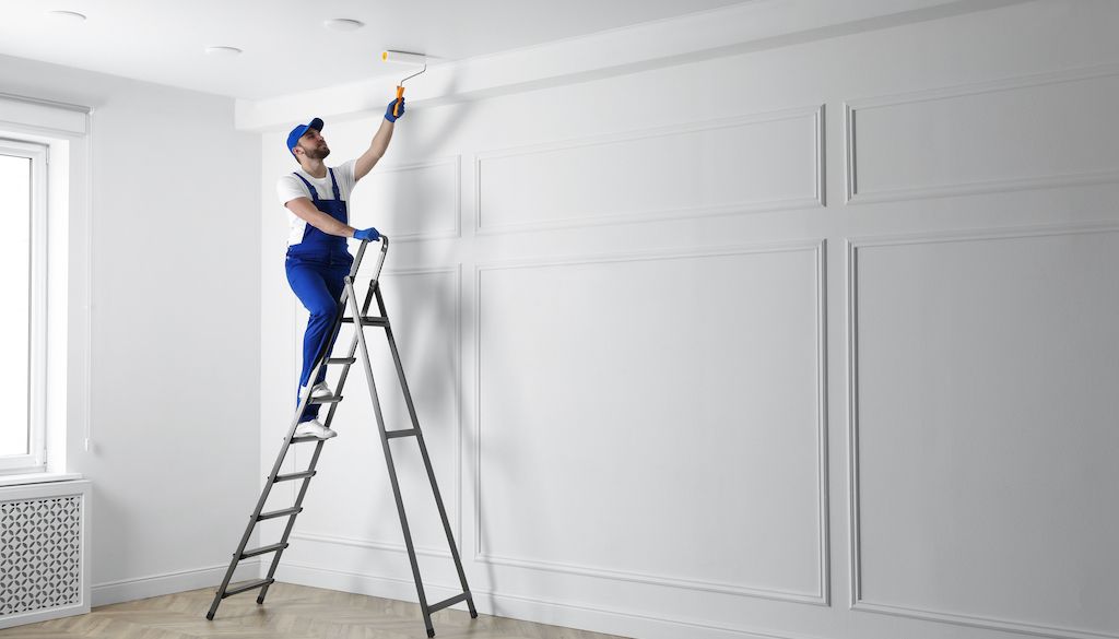 painter on ladder painting room ceiling white