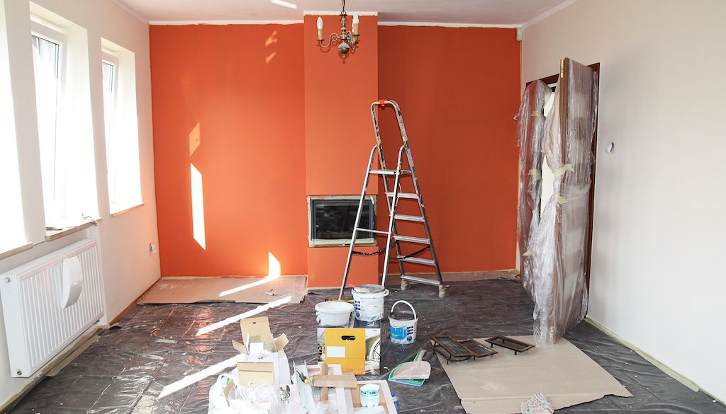 unfinished painted room with orange wall and paint supplies everywhere