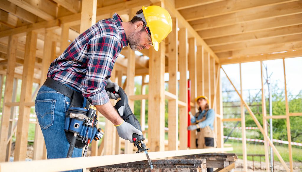 construction worker building wood frame house