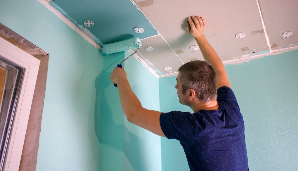 man painting ceiling in house blue