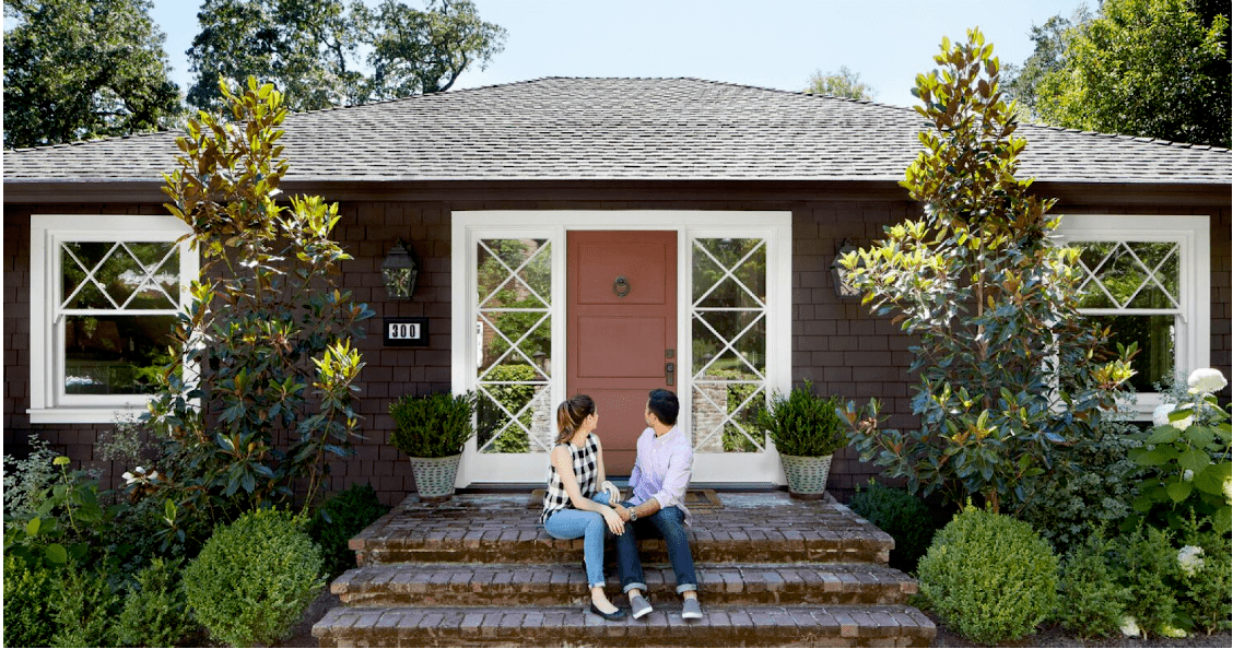 couple sitting in front of house and looking at front door