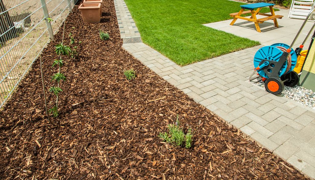 mulch in backyard with grass and patio
