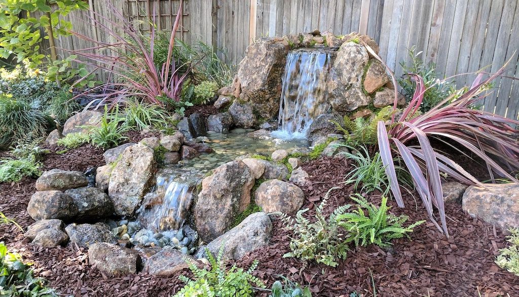 waterfall water feature with boulders in backyard landscape design