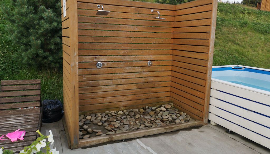 wooden outdoor shower in backyard near pool