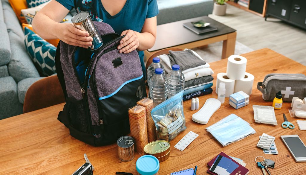 woman putting supplies in emergency kit bag