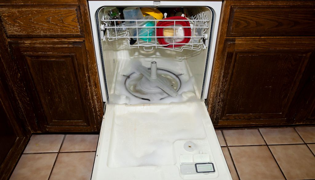 open dishwasher with soap suds and water in the bottom that won't drain