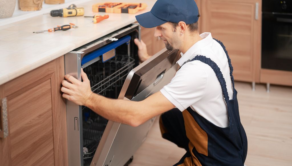 appliance technician replacing or repairing dishwasher