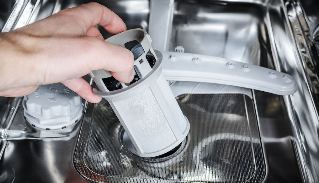 hand pulling out and removing dishwasher filter