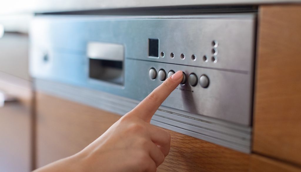 finger pressing button to turn on dishwasher cycle