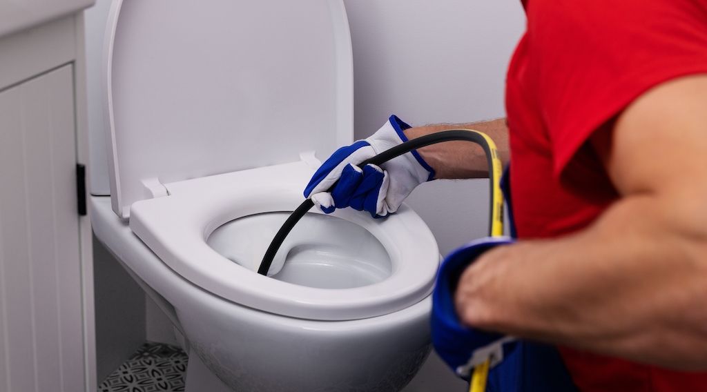 plumber fixing a clogged toilet