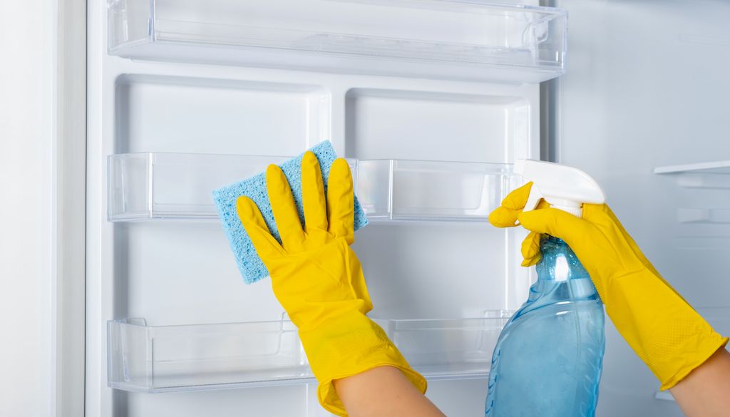 cleaning fridge interior with sponge and gloves on
